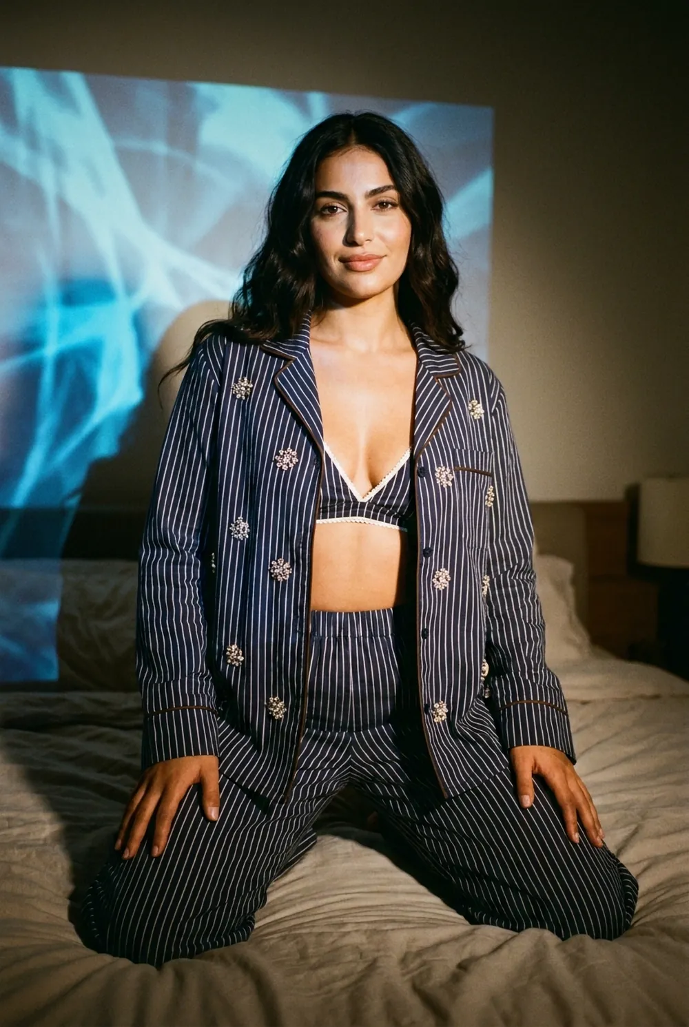 Kneeling on a bed at night in the crystal pinstripe set